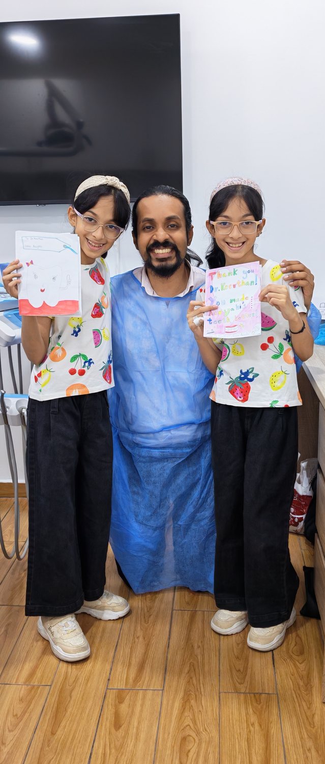 Dr. Keerthan with two young patients holding thank-you drawings