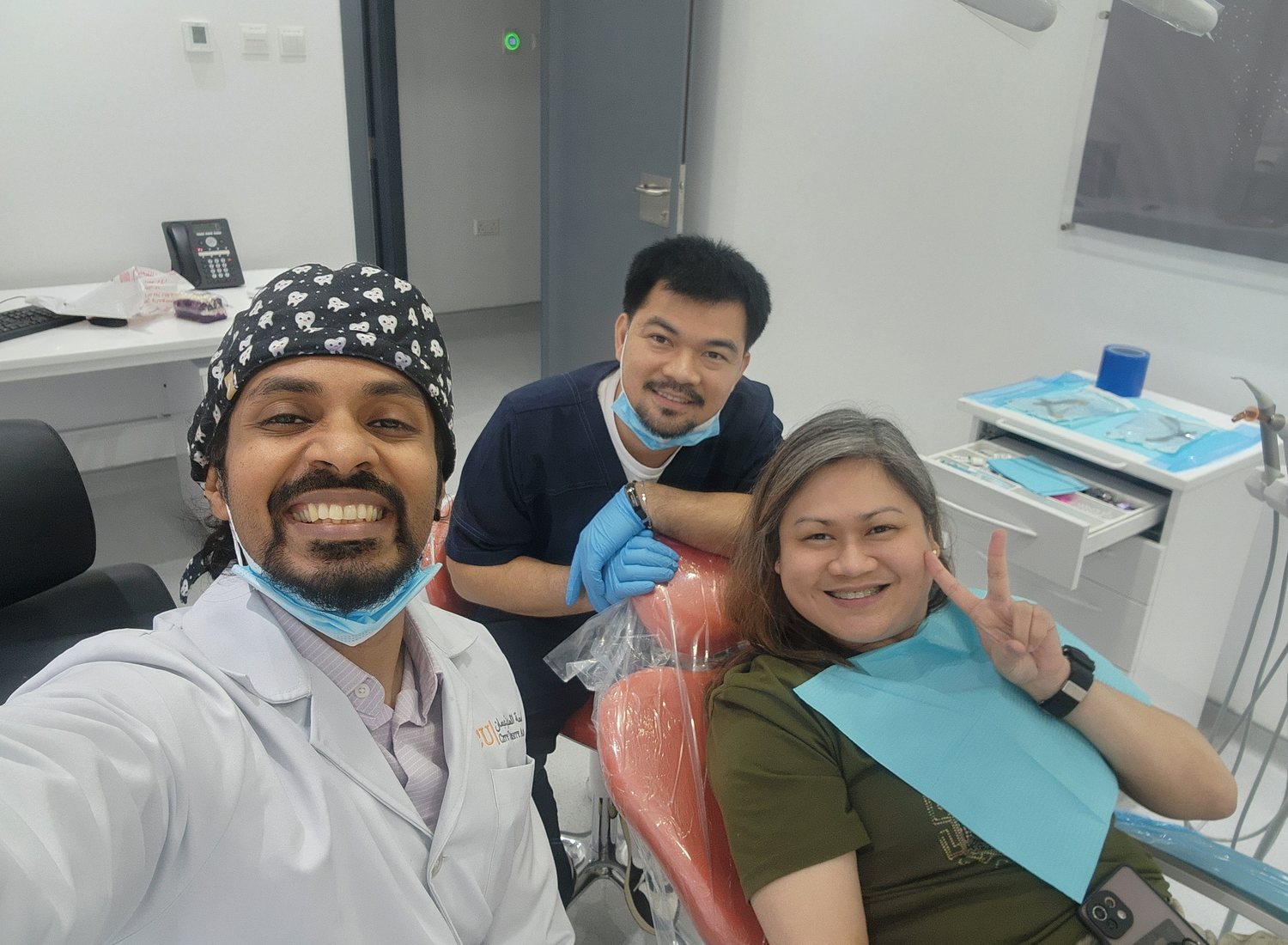 Dr. Keerthan and a colleague with a smiling patient in the chair