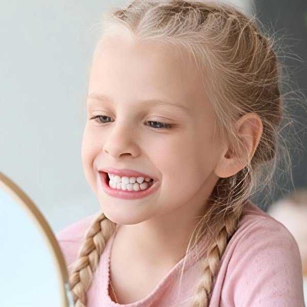 Smiling girl checking her teeth in a mirror