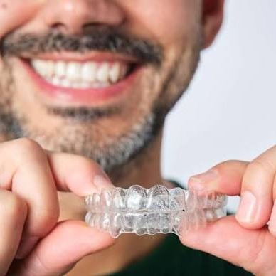 Smiling man holding a clear retainer