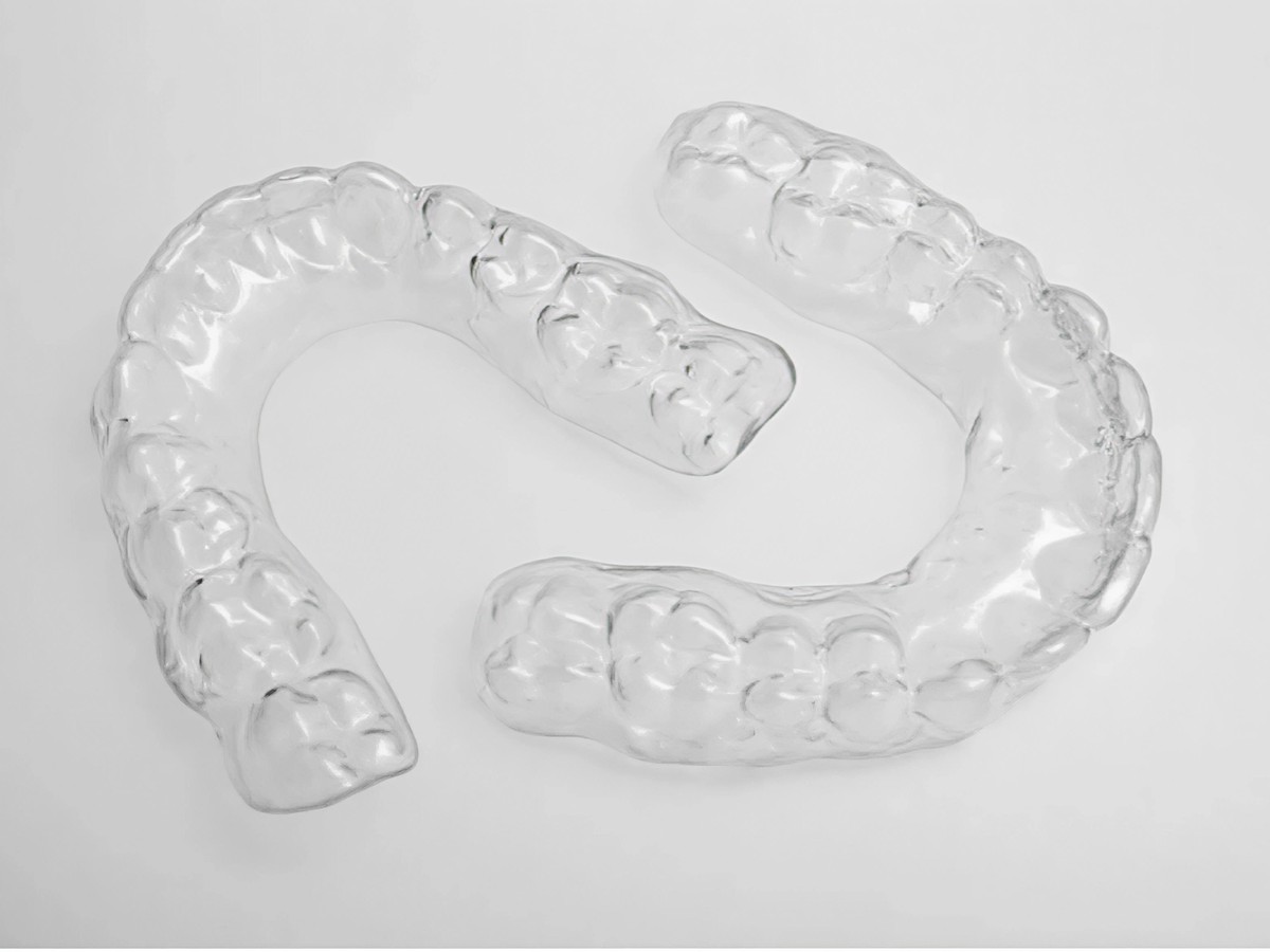 Two clear Essix retainer shells, upper and lower, on a plain background
